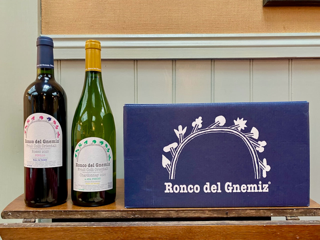 Two wine bottles and a box labeled 'Ronco del Gnemiz' on a wooden surface.
